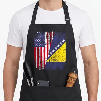 Bosnian american flag apron - Distressed diagonal split print of USA and Bosnia flags in red white blue and yellow — shown on a black cotton canvas apron against a white background