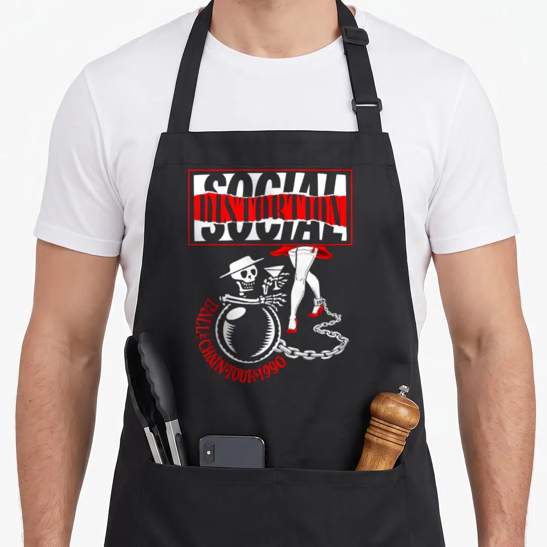 Social hubby apron - Social Distortion Ball and Chain Tour 1990 text above skeleton and red heels with chain — shown on a black cotton canvas apron against a white background