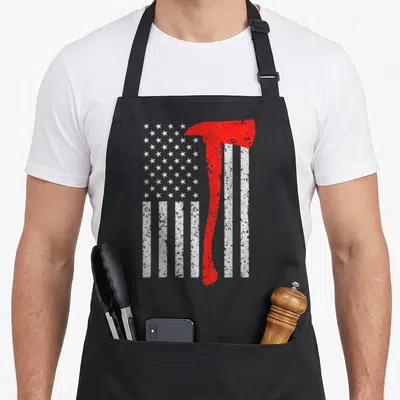 Flag firefighter apron - Red fire axe superimposed on distressed white US flag stars and stripes — shown on a black cotton canvas apron against a white background