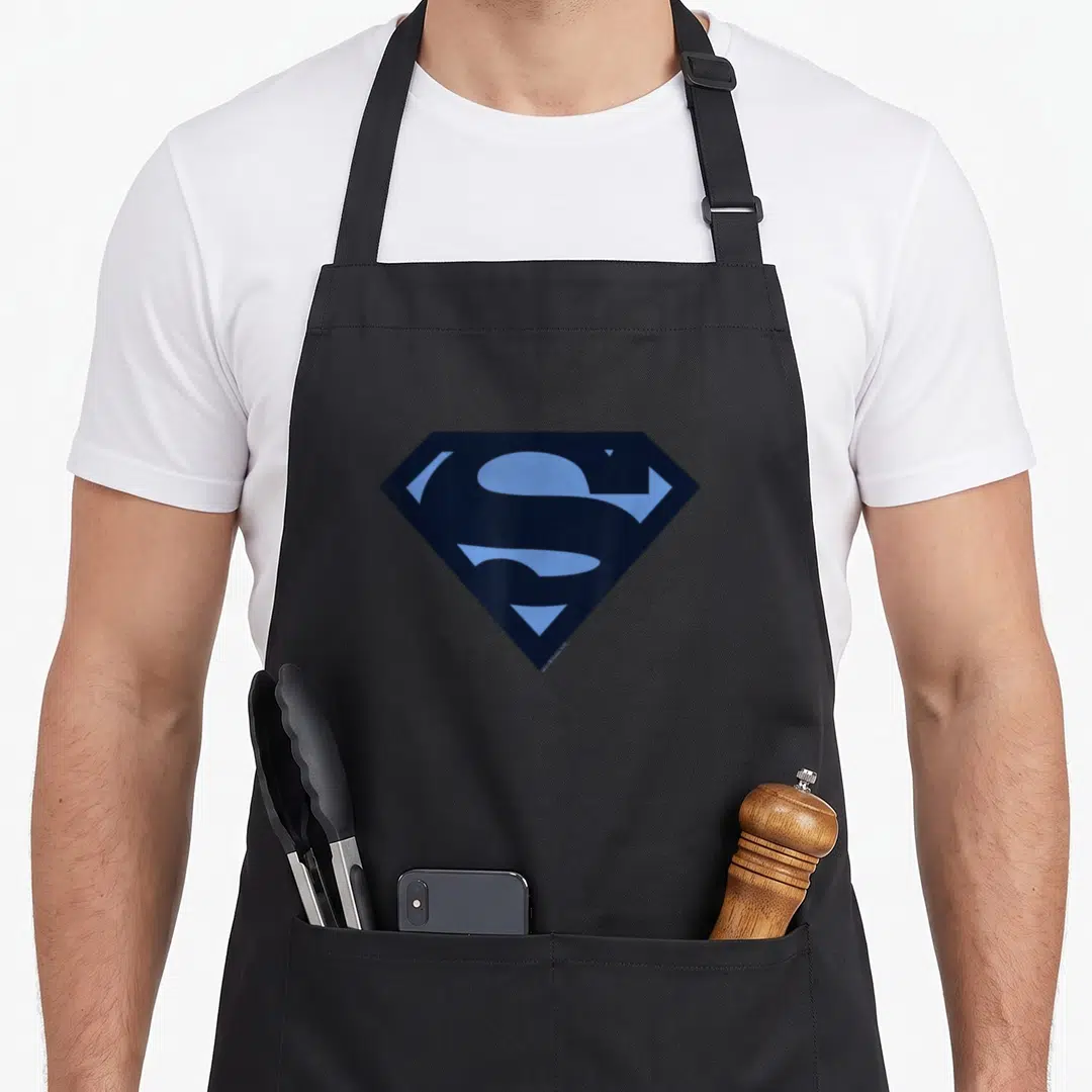 Blue son life apron - Dark blue diamond shape with light blue stylized S inside, minimalist superhero logo — shown on a black cotton canvas apron against a white background