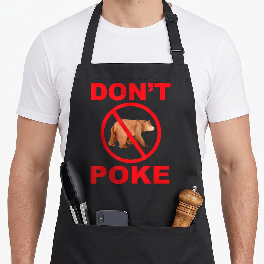 Superhero bear apron - Red Don't Poke text surrounding brown bear in prohibition circle — shown on a black cotton canvas apron against a white background