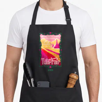 Wicked tulip apron - Munchkinland's Famous Tulip Fair text over pink yellow red flower field with green floral border — shown on a black cotton canvas apron against a white background