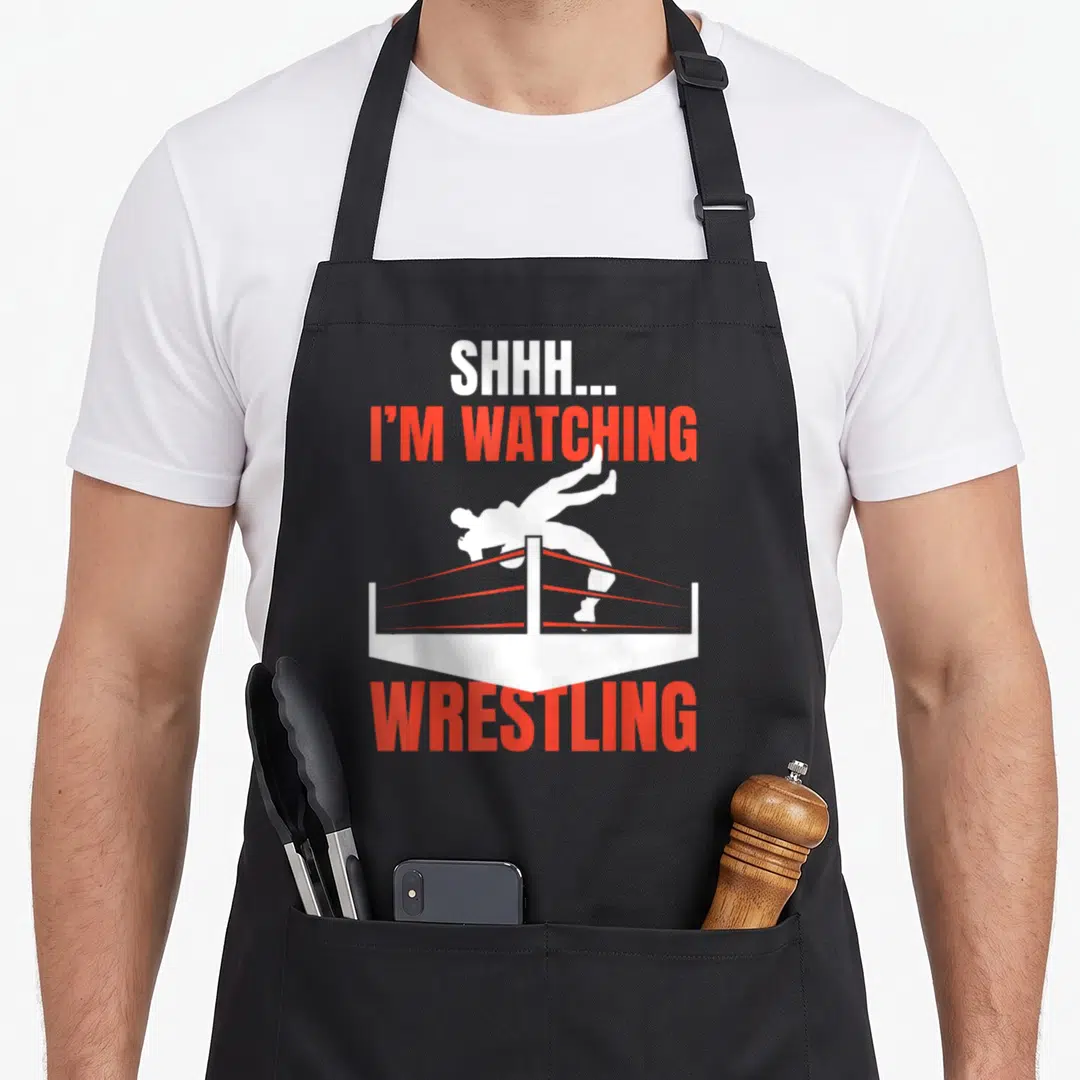 Watching wrestling apron - Minimalist wrestler jumping red ring with text SHHH I'M WATCHING WRESTLING — shown on a black cotton canvas apron against a white background