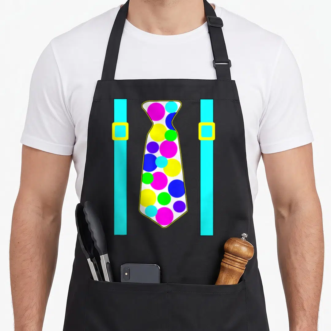 Polka tie apron - Cartoon white tie with cyan pink and yellow polka dots between cyan suspenders with yellow buckles — shown on a black cotton canvas apron against a white background