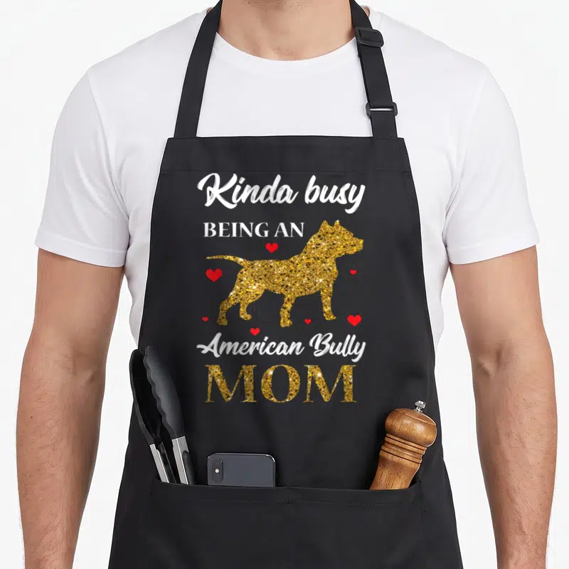 Pitty mama apron - Gold glitter American Bully dog silhouette surrounded by red hearts and white stacked text — shown on a black cotton canvas apron against a white background