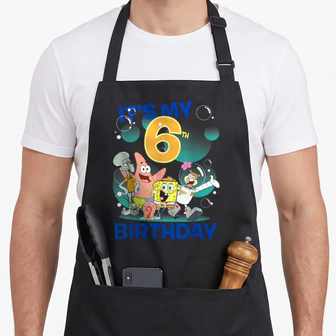 Squarepant 6th birthday apron - SpongeBob and friends cluster under IT'S MY 6TH BIRTHDAY text with scattered bubbles — shown on a black cotton canvas apron against a white background