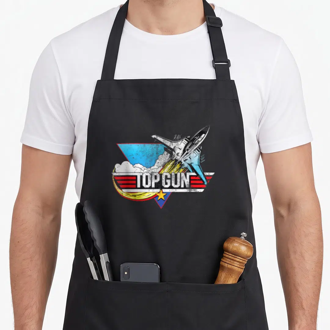 Gun flying apron - Top Gun fighter jet graphic with blue red triangle and yellow star — shown on a black cotton canvas apron against a white background