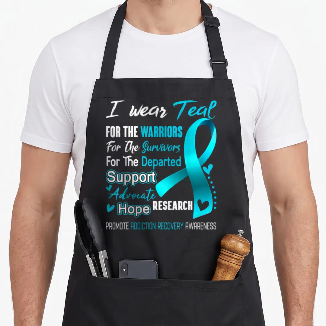 Awareness addiction recovery apron - Stacked white and teal text reading I wear Teal For The Warriors next to a large — shown on a black cotton canvas apron against a white background