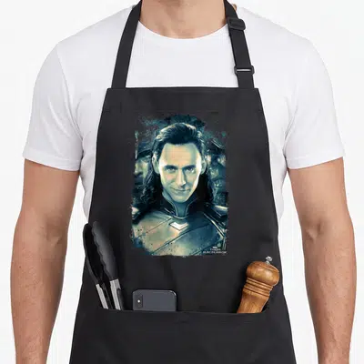 Ragnarok distressed apron - Loki portrait in teal white black with Marvel Thor Ragnarok text — shown on a black cotton canvas apron against a white background