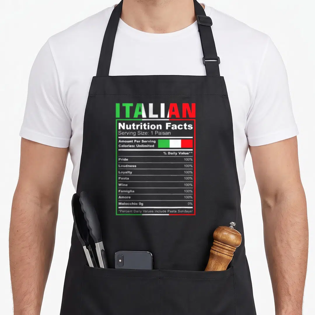 Nutrition italian aprons - Italian nutrition facts label with pride, pasta, wine, and famiglia percentages in green — shown on a black cotton canvas apron against a white background