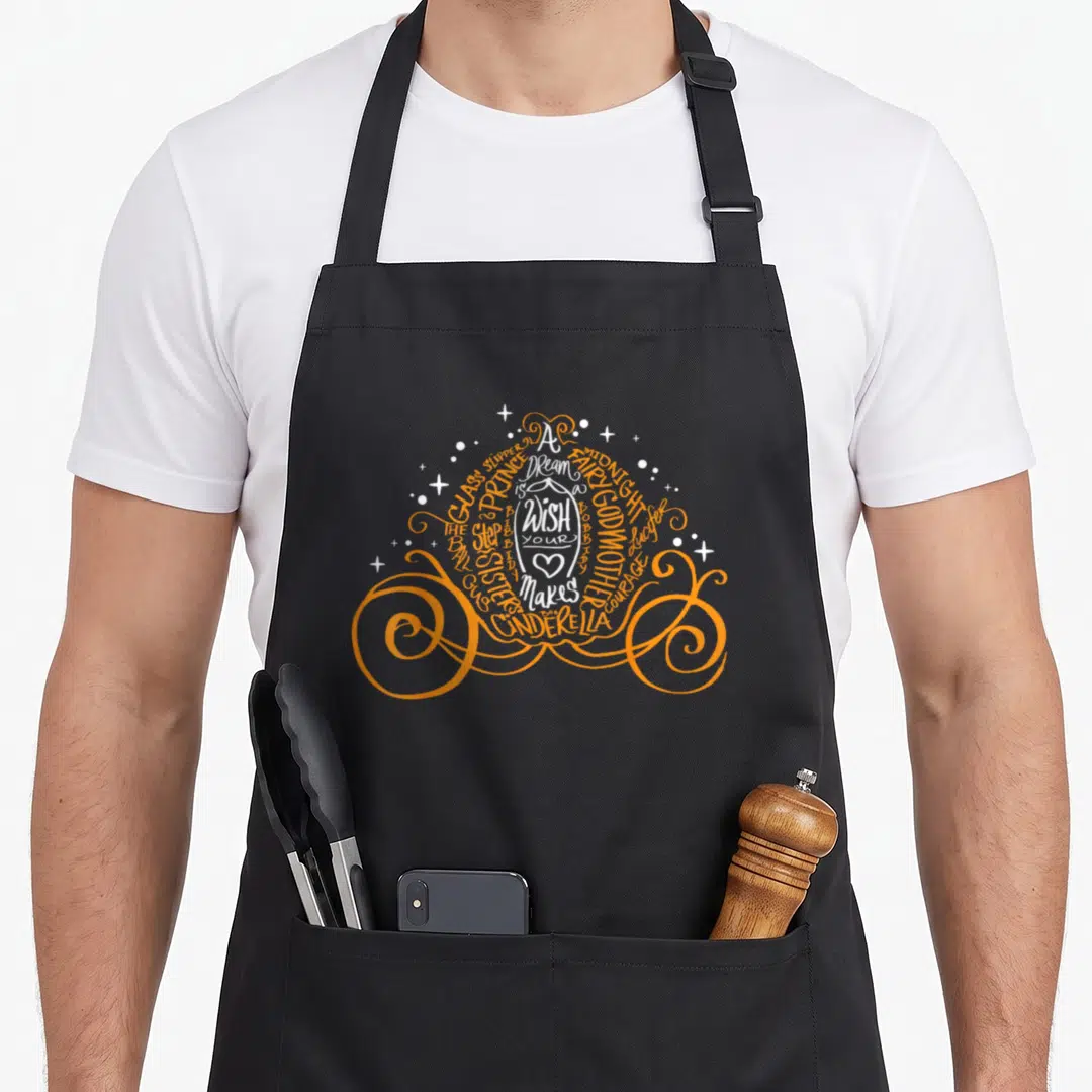 Cinderella halloween apron - Orange and white typography forming a pumpkin carriage with story keywords and a central — shown on a black cotton canvas apron against a white background