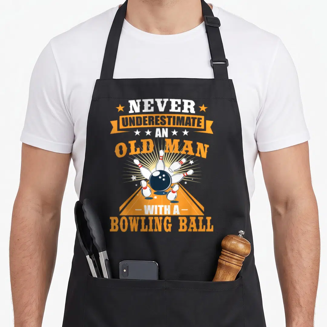 Underestimate bowling apron - Retro text Never Underestimate An Old Man With A Bowling Ball above blue ball and white — shown on a black cotton canvas apron against a white background