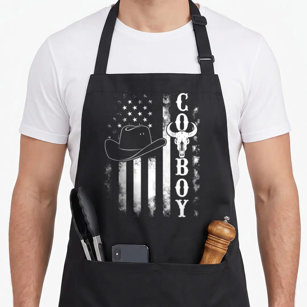 Western southern aprons - White distressed flag with cowboy hat, bull skull, and vertical COBOY text — shown on a black cotton canvas apron against a white background