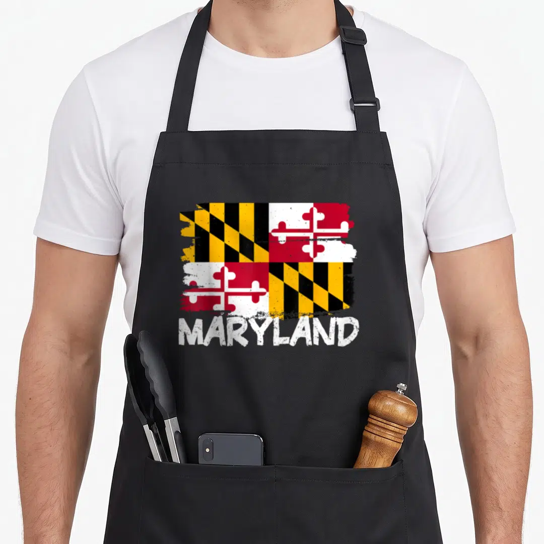 Funny flag maryland eastern apron - Distressed Maryland state flag graphic and white MARYLAND text in black, yellow — shown on a black cotton canvas apron against a white background