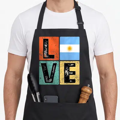 Flag argentine pride apron - Distressed LOVE text in orange blue green and yellow squares with Argentina flag in top — shown on a black cotton canvas apron against a white background