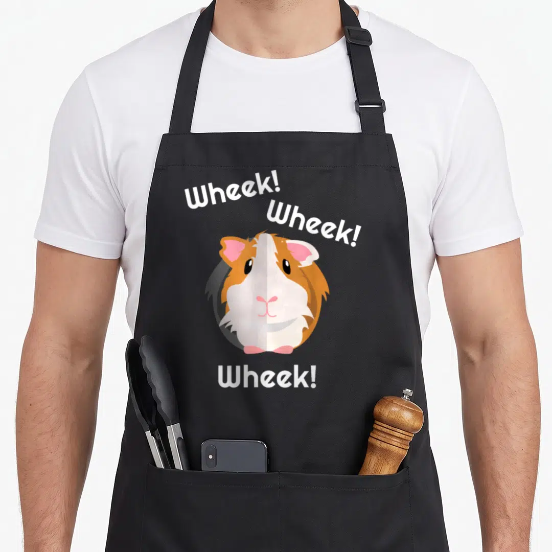 Wheek pig apron - Cartoon guinea pig face with white text reading Wheek above and below — shown on a black cotton canvas apron against a white background