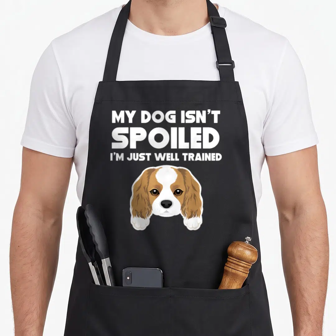 Spoiled king apron - Cartoon brown and white dog head with two paws under three lines of white text reading My Dog — shown on a black cotton canvas apron against a white background