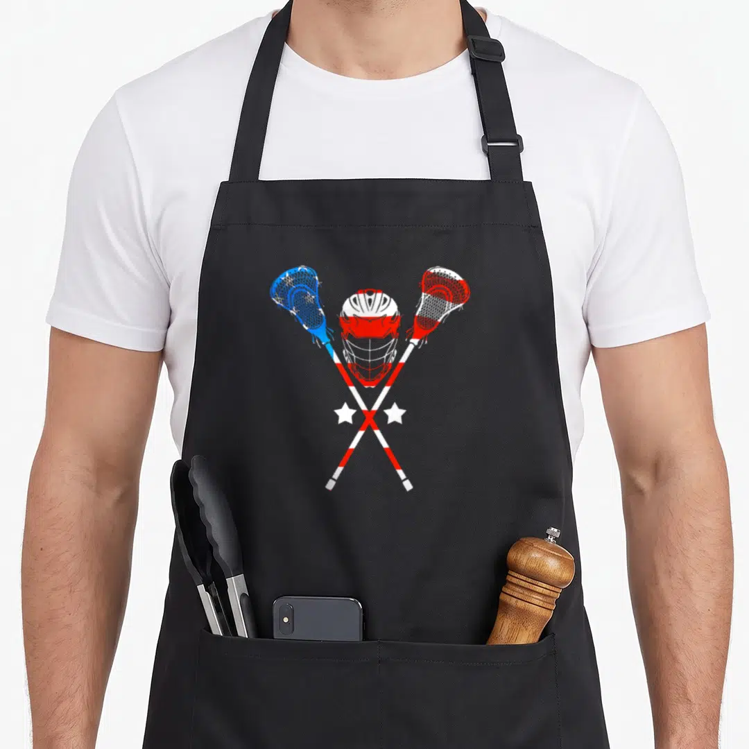 Patriotic lacrosse 4th of july apron - Red white and blue lacrosse helmet between crossed sticks with two white stars — shown on a black cotton canvas apron against a white background