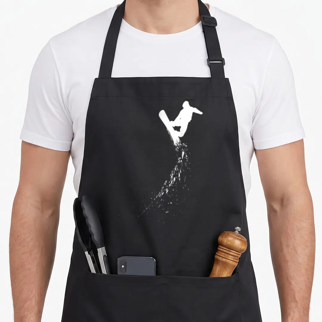 Freestyle boarding apron - White snowboarder silhouette with downward snow splatter trail on grey background — shown on a black cotton canvas apron against a white background