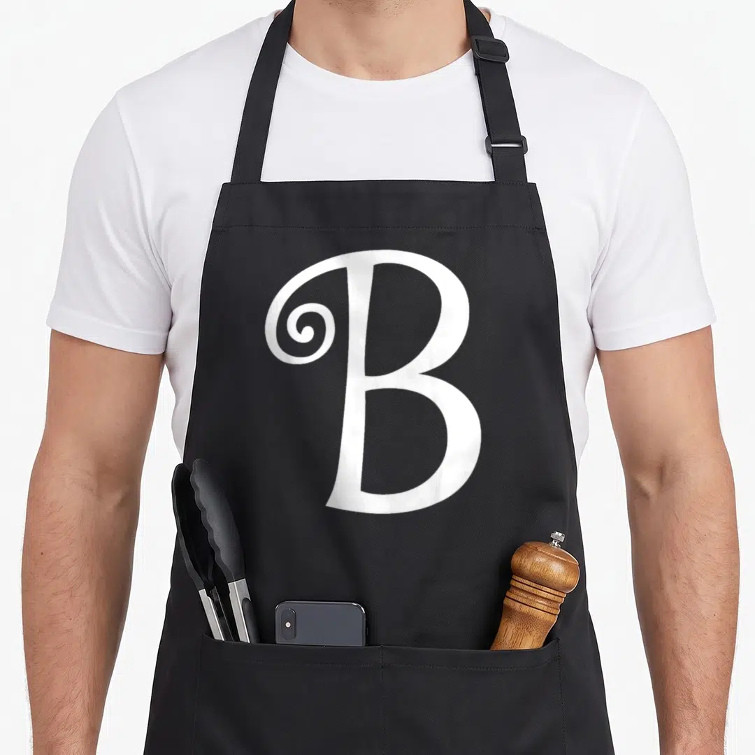 Letter brittany apron - White serif letter B with decorative swirl on black bib apron — shown on a black cotton canvas apron against a white background