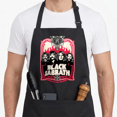 Sabbath flame apron - Four band members in black line art before red flames with BLACK SABBATH text and ornate border — shown on a black cotton canvas apron against a white background