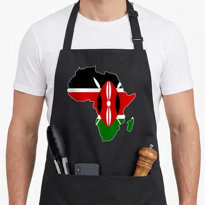 Kenyan pride apron - Africa map filled with Kenyan flag colors black red green white shield and spears — shown on a black cotton canvas apron against a white background