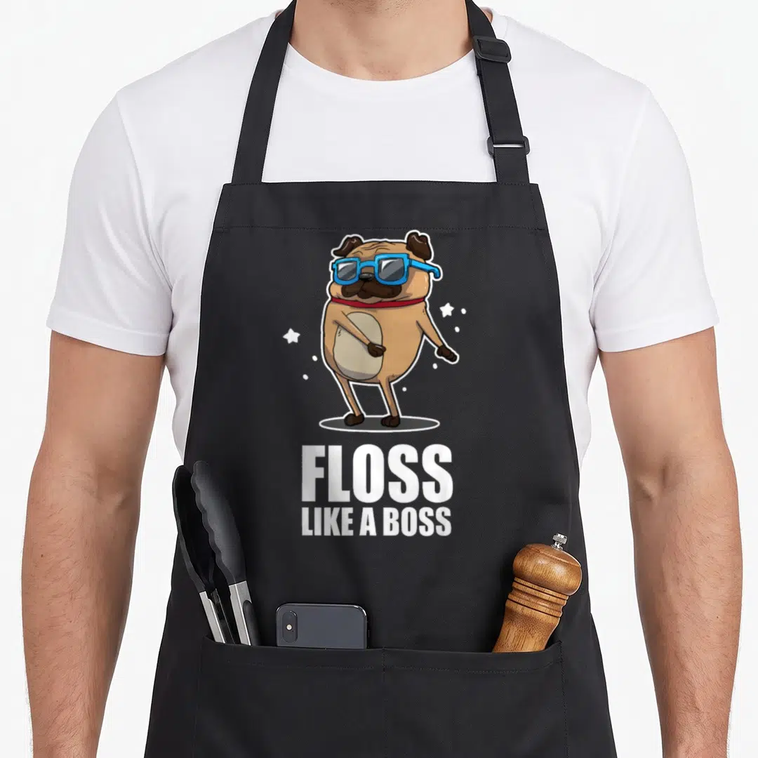 Floss boss apron - Cartoon tan pug with blue sunglasses and red collar above white FLOSS LIKE A BOSS text — shown on a black cotton canvas apron against a white background