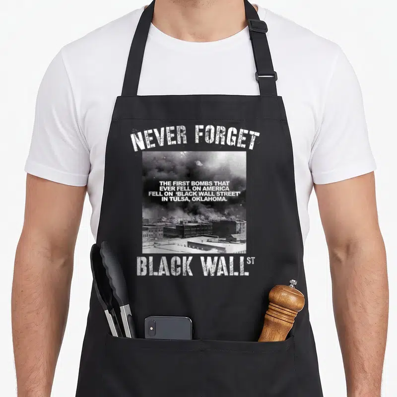 Wall black-owned aprons - Distressed text NEVER FORGET over grayscale photo of burning buildings with quote about Tulsa — shown on a black cotton canvas apron against a white background