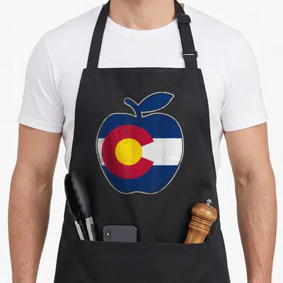 Colorado teacher apron - Distressed apple filled with blue white red and yellow Colorado flag stripes and circle — shown on a black cotton canvas apron against a white background