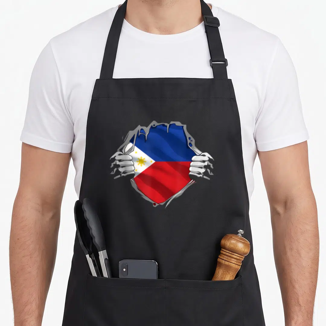 Sun pride apron - Two hands ripping grey surface to reveal blue red white yellow Philippine flag — shown on a black cotton canvas apron against a white background