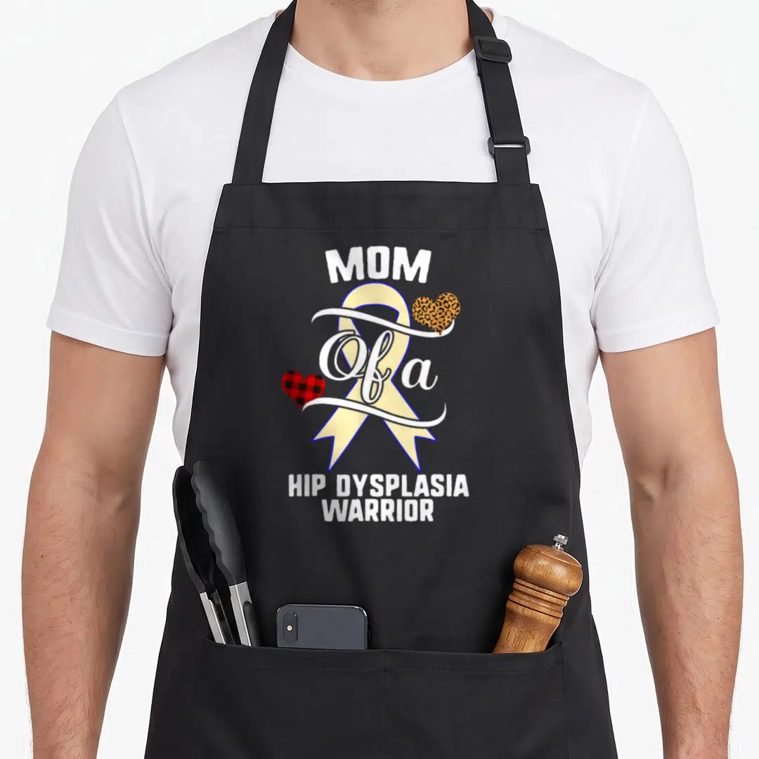 Hip buffalo plaid apron - MOM Of a HIP DYSPLASIA WARRIOR text with cream ribbon and buffalo plaid and leopard hearts — shown on a black cotton canvas apron against a white background