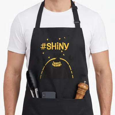 Wreck crab apron - Yellow #SHiNY text above a black cartoon crab with small yellow triangles — shown on a black cotton canvas apron against a white background
