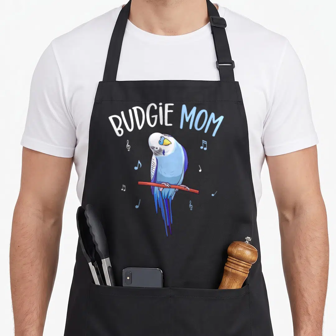 Budgie parakeet lover apron - Blue budgie perched on red branch with scattered musical notes and arched text — shown on a black cotton canvas apron against a white background