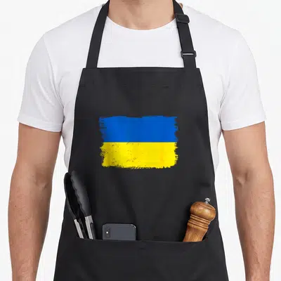 Cool ukraine ukrainian aprons - Rectangular blue and yellow flag with distressed paint effect on black fabric — shown on a black cotton canvas apron against a white background