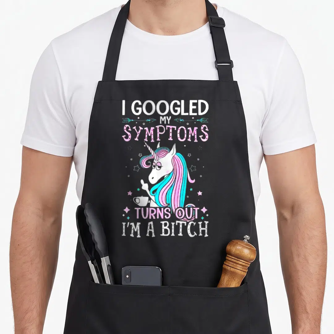 Googled i turn grills on apron - Cartoon unicorn holding cup surrounded by stars with text I Googled My Symptoms Turns — shown on a black cotton canvas apron against a white background