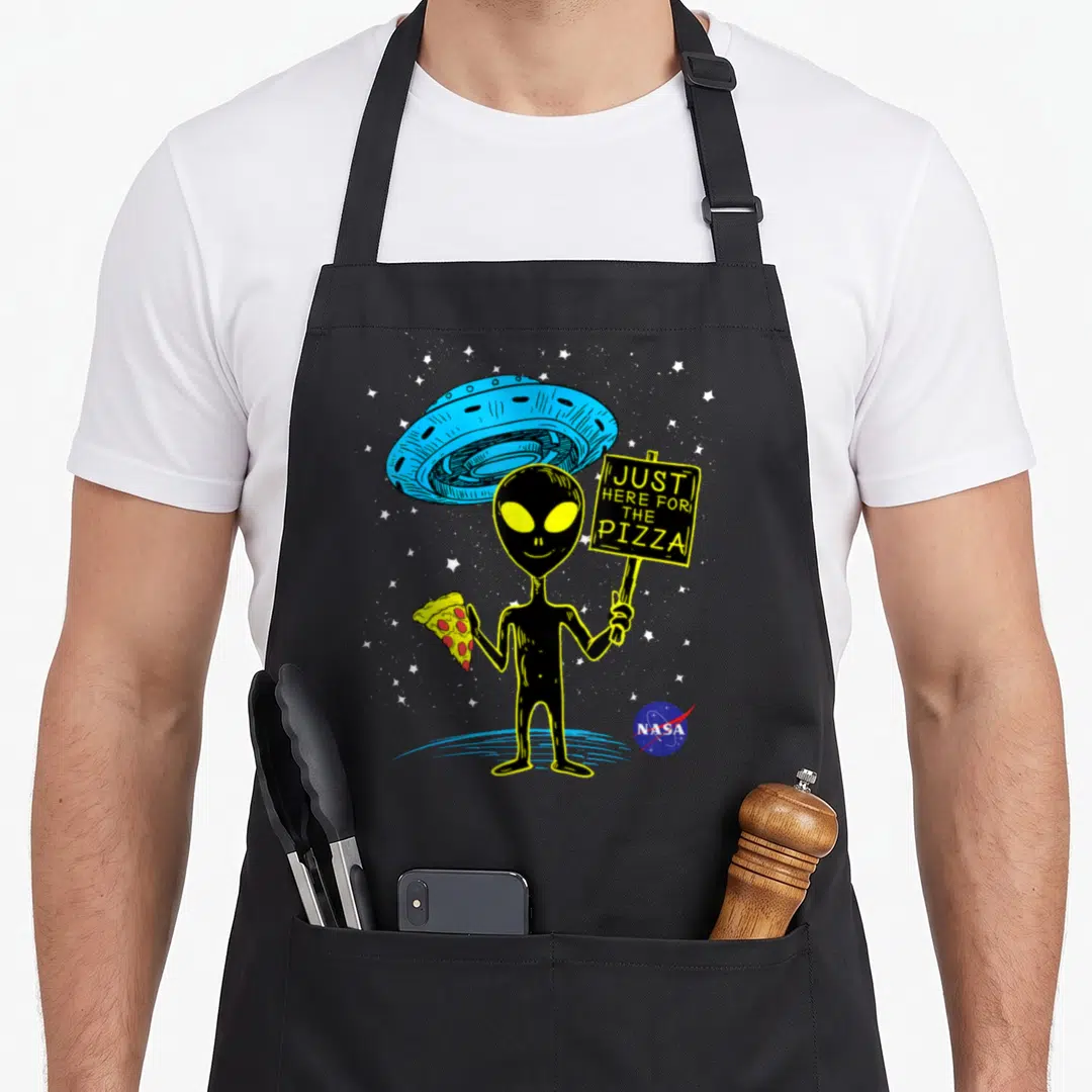 Ufo nasa apron - Cartoon alien holding pizza slice and sign saying just here for the pizza under blue UFO — shown on a black cotton canvas apron against a white background