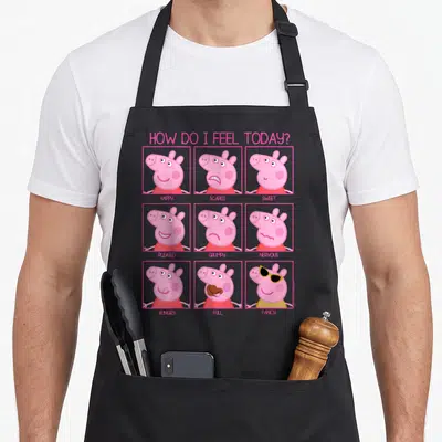 Feel crazy pig man apron - Peppa Pig 3x3 grid faces labeled happy scared sweet pleased grumpy nervous hungry full fancy — shown on a black cotton canvas apron against a white background
