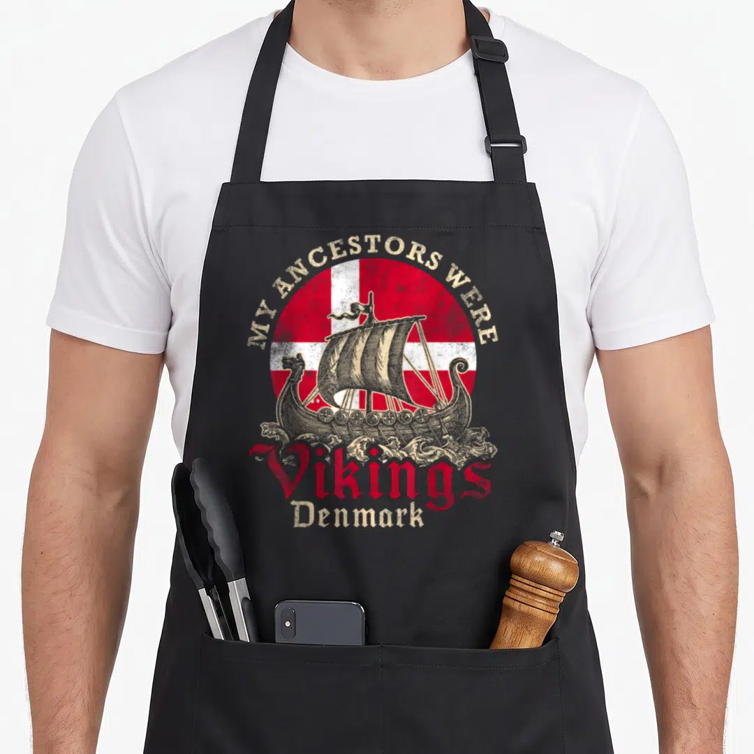 Danish viking apron - Circular red and white flag with distressed viking ship and My Ancestors Were Vikings text — shown on a black cotton canvas apron against a white background