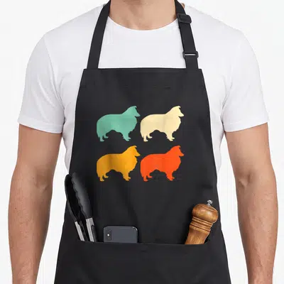 Funny sheltie dog apron - Four Sheltie silhouettes in teal cream yellow orange arranged in 2x2 grid — shown on a black cotton canvas apron against a white background