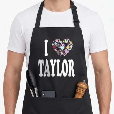 Taylor colorful aprons - I TAYLOR text with large heart made of small pink blue purple yellow white hearts — shown on a black cotton canvas apron against a white background