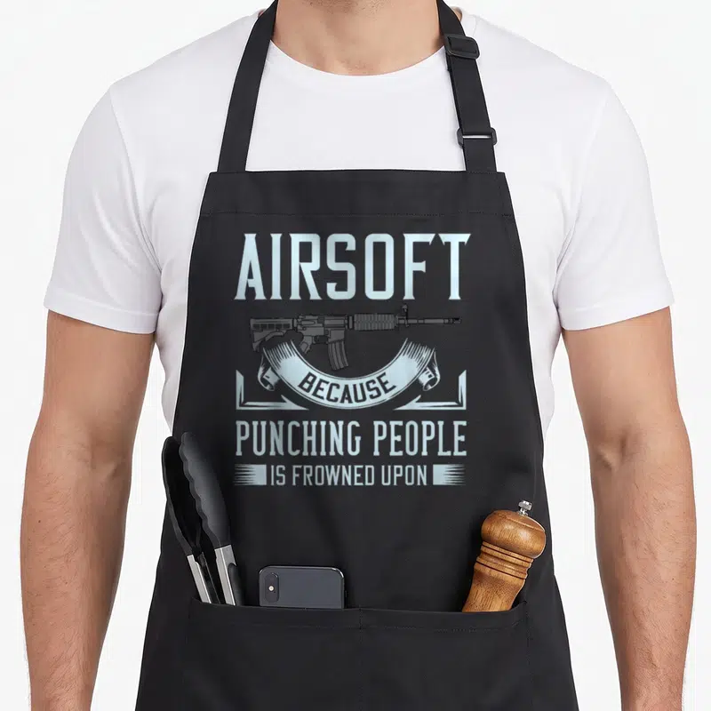 Airsoft gun apron - Rifle illustration and text airsoft because punching people is frowned upon in blue and grey — shown on a black cotton canvas apron against a white background
