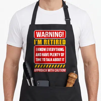 Gag retirement apron - Red and yellow warning sign reading I'm retired I know everything — shown on a black cotton canvas apron against a white background