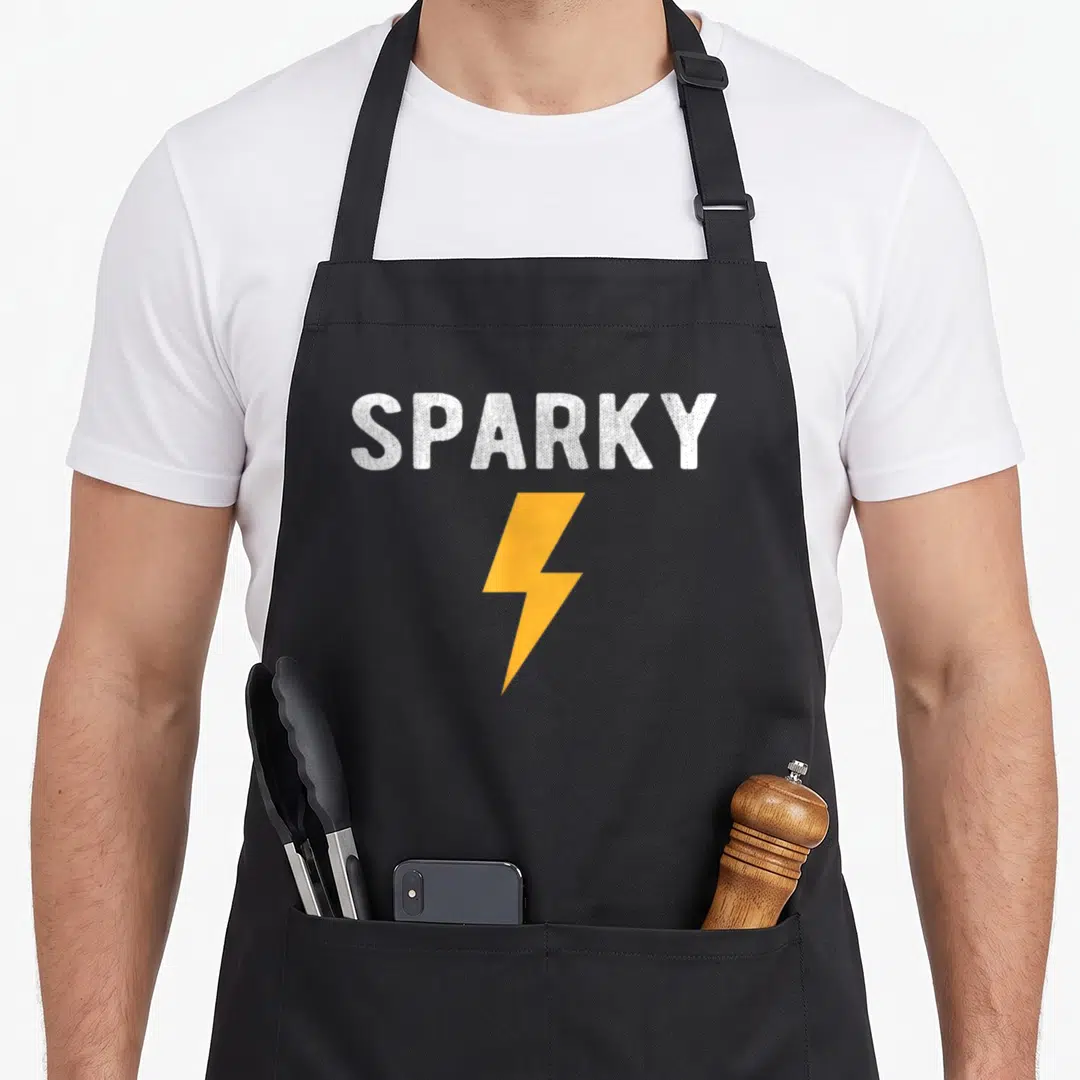 Sparky electrician apron - White SPARKY text above an orange lightning bolt graphic on grey background — shown on a black cotton canvas apron against a white background