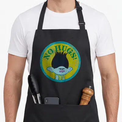 Hug branch troll apron - Grumpy cartoon troll face with NO HUGS! text in green on yellow circle with blue border — shown on a black cotton canvas apron against a white background