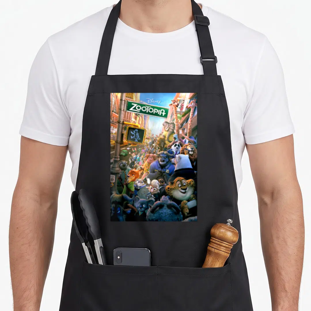 Funny poster novelty apron - Disney ZOOTOPIA logo above a crowd of anthropomorphic animals near a pedestrian crossing — shown on a black cotton canvas apron against a white background
