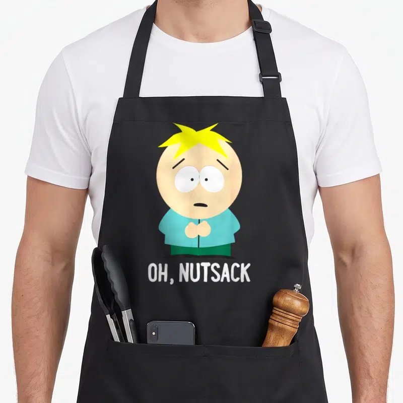 Nutsack butter apron - Butters Stotch cartoon figure above white OH NUTSACK text in blue yellow peach white — shown on a black cotton canvas apron against a white background