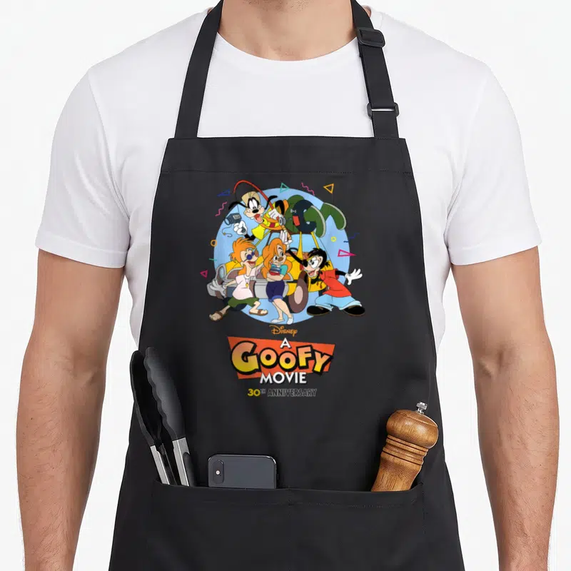 Movie road apron - Goofy and friends in light blue circle with A Goofy Movie 30th Anniversary text and geometric shapes — shown on a black cotton canvas apron against a white background