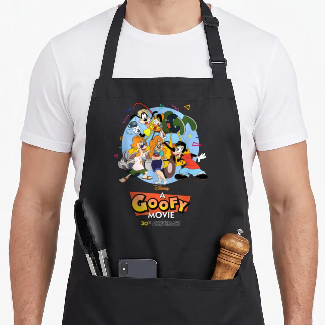 Movie road apron - Goofy and friends in light blue circle with A Goofy Movie 30th Anniversary text and geometric shapes — shown on a black cotton canvas apron against a white background