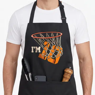 Basketball celebration birthday apron - I'M 10 text with orange basketball falling through white hoop net — shown on a black cotton canvas apron against a white background