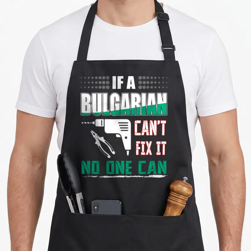 Fix bulgarian boy apron - Stacked text IF A BULGARIAN CAN'T FIX IT NO ONE CAN with white drill pliers and grey dots — shown on a black cotton canvas apron against a white background